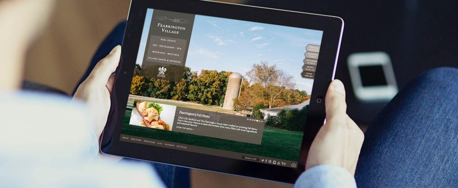 Person holding a tablet device showing the Fearrington Village website